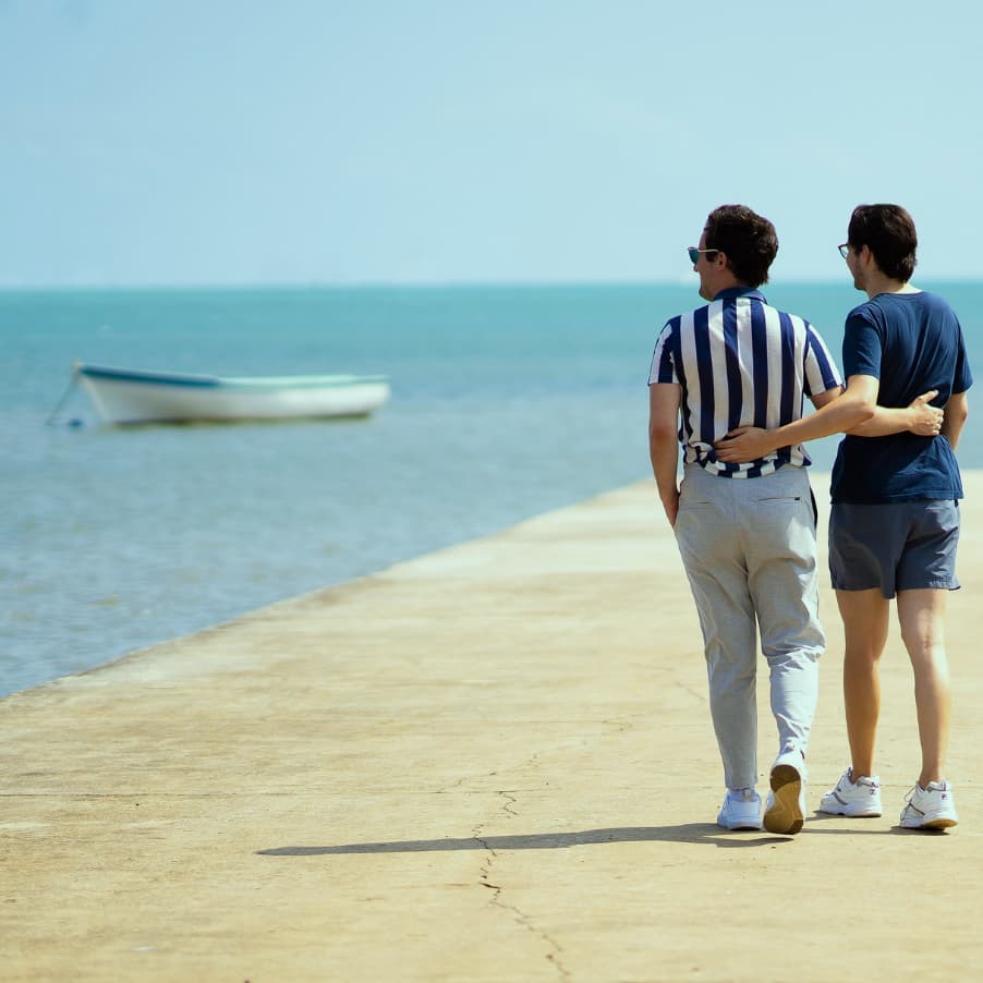 A couple walking along a harbour looking out at the water
