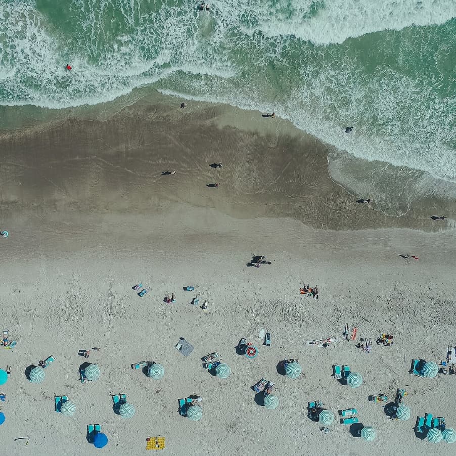 Aerial view of beach umbrellas on a beach with waves breaking on the shore