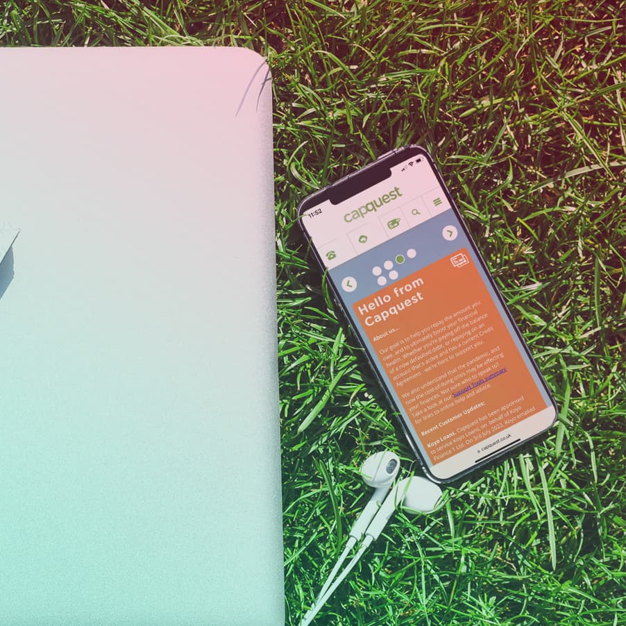 Smartphone lying on grass showing Capquest homepage on screen