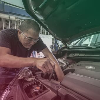 A mechanic changing the oil under the hood of a car