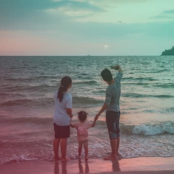 A couple with a young child taking a selfie at the beach