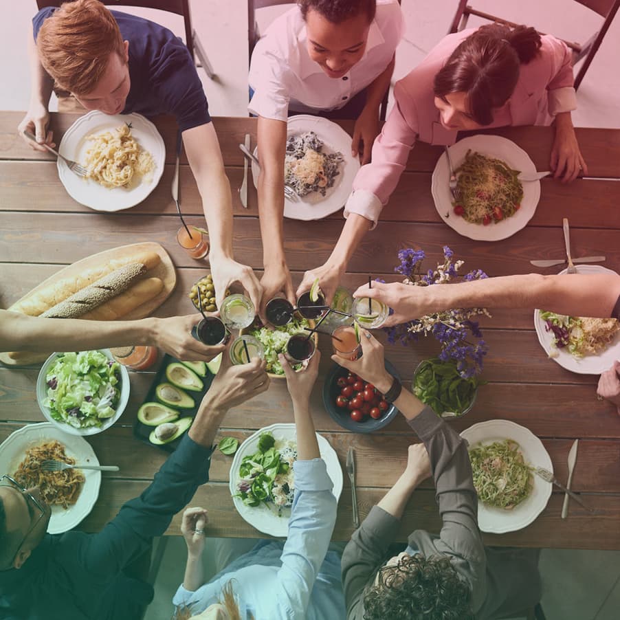 birds eye view photo of a group of people seated round a table ready to eat a meal clinking glasses